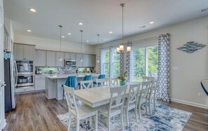 A modern kitchen with white cabinets, a central island, and blue chairs. - Modern 5 Bedroom 4 Full Bath Bethany Beach Home (Ocean View)