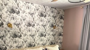 A bedroom with a floral wallpaper, a bed with a dark blue bedspread, and two bedside tables. - Cherry Bend Getaway (Traverse City)
