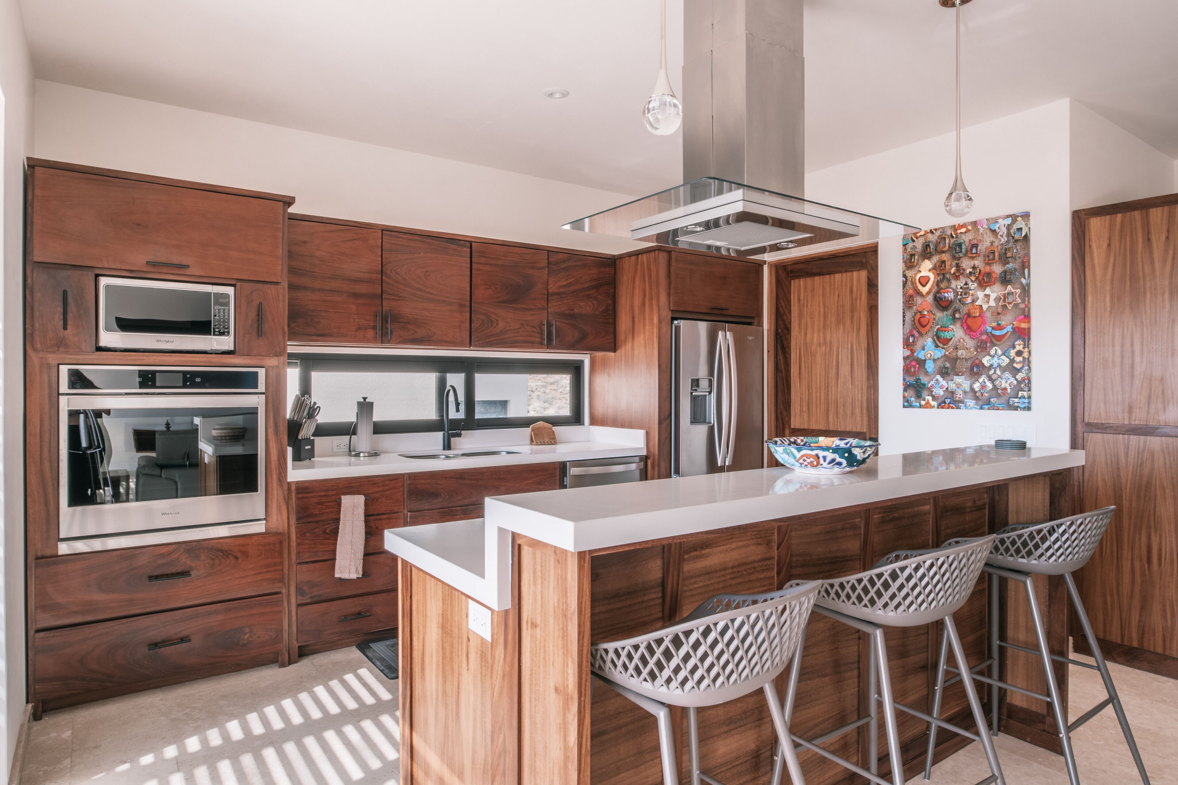 A modern kitchen with wooden cabinets, stainless steel appliances, and a central island with bar stools.