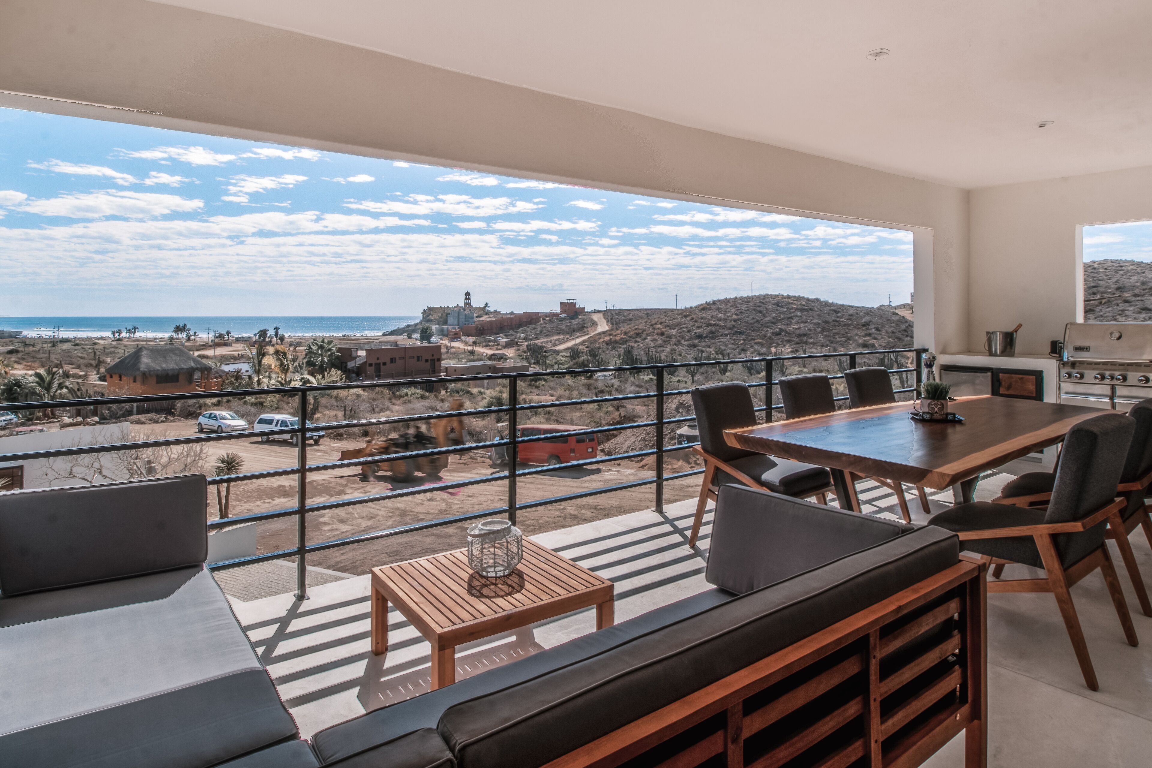 Un balcon doté d’un espace repas, d’un barbecue et offrant une vue sur la plage et les bâtiments situés au loin.