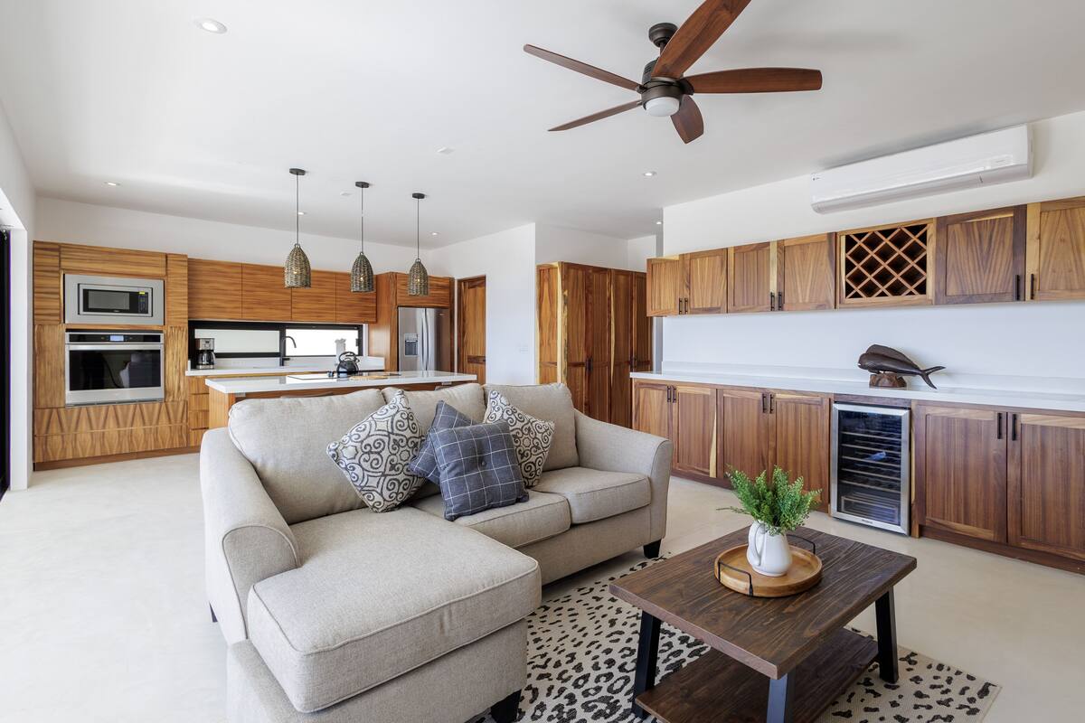 A modern kitchen with wooden cabinets, a built-in microwave, and a ceiling fan.