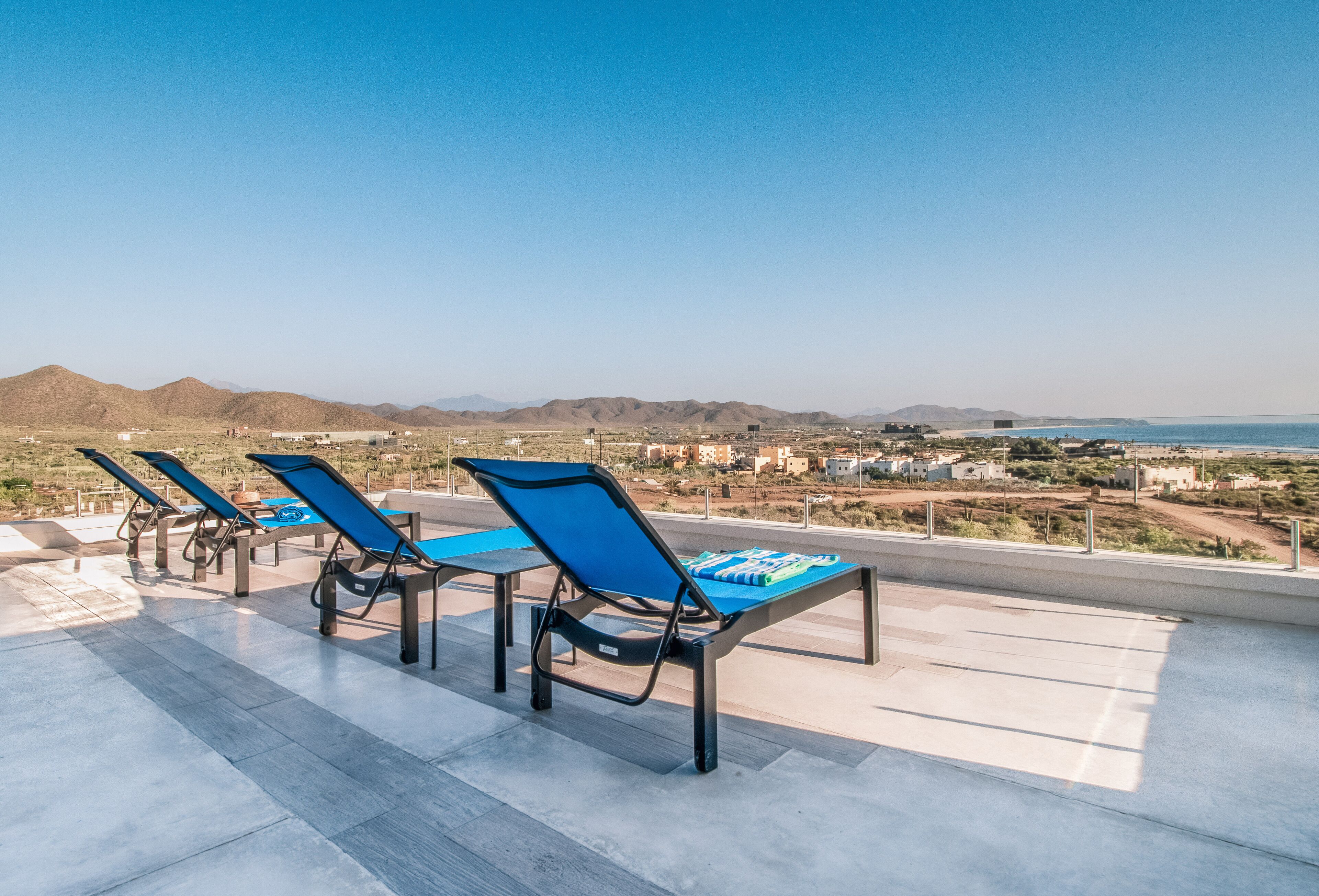 Une terrasse sur le toit, dotée de chaises longues et offrant une vue sur la ville et les montagnes.