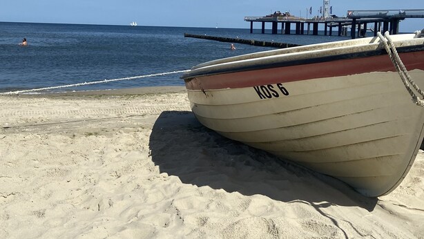 A boat with the number "KOS 6" on a sandy beach with a pier in the background. - Ferienbungalow Ancora in Koserow (Koserow)