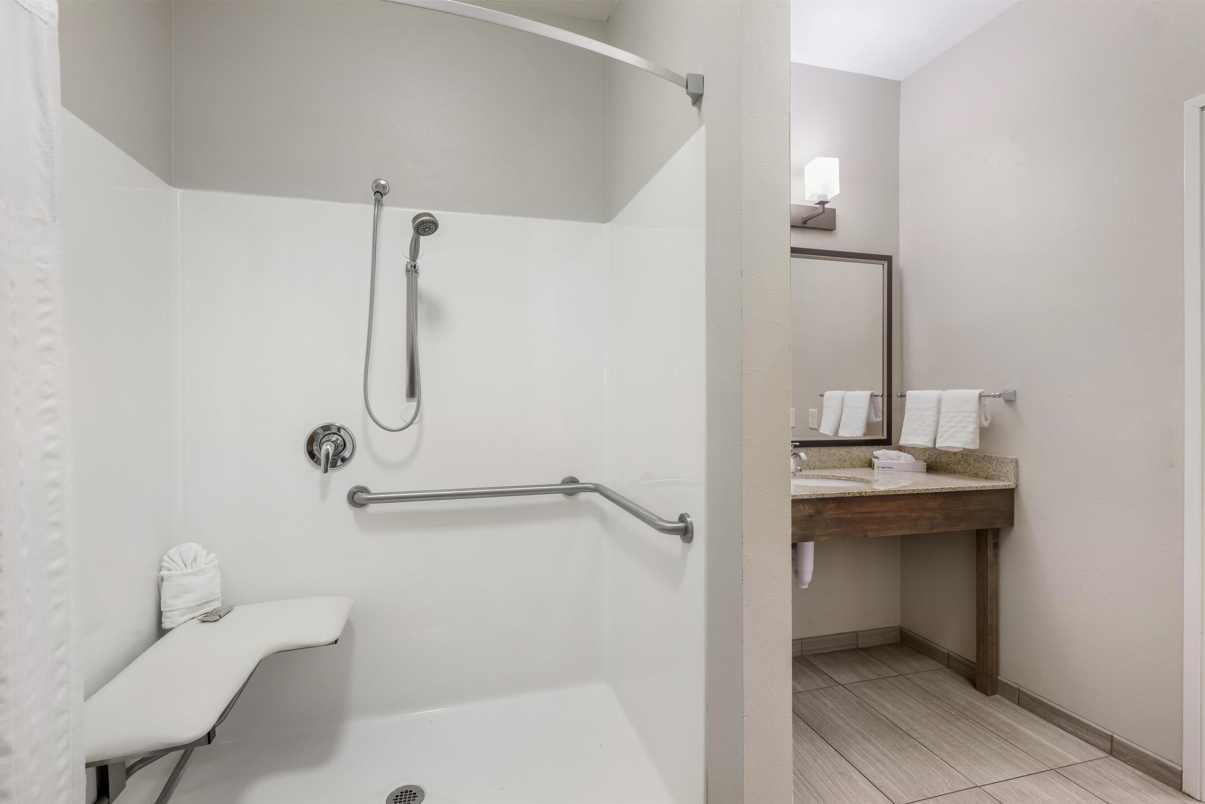 A bathroom with a shower, a toilet, and a sink with a mirror.