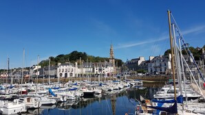 A marina with numerous boats docked, a prominent church with a tower, and residential buildings in the background.