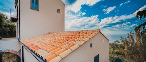 Un bâtiment avec un toit recouvert de tuiles, une petite fenêtre et une antenne parabolique.