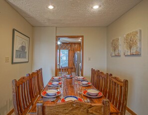 A dining room with a long wooden table set for a meal, flanked by wooden chairs. - Stemwinder 6A, 3 Bedrooms Plus Bonus Sleeping Alcove, 2 1/2 Baths (Snowshoe)