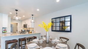 A dining area with a round table set for six, surrounded by wooden chairs. A vase with yellow flowers is placed in the center. - Etta Place 102 by Exceptional Stays (Telluride)