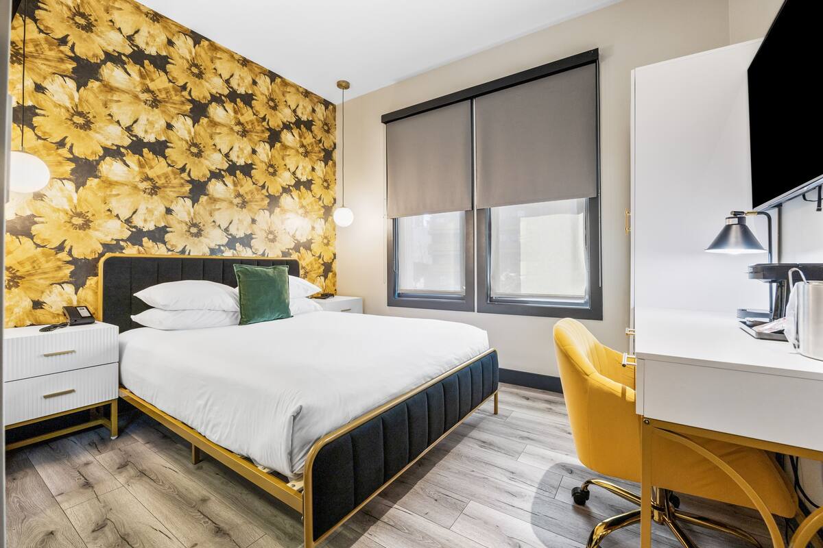 A bedroom with a bed, bedside tables, a desk, and a chair.