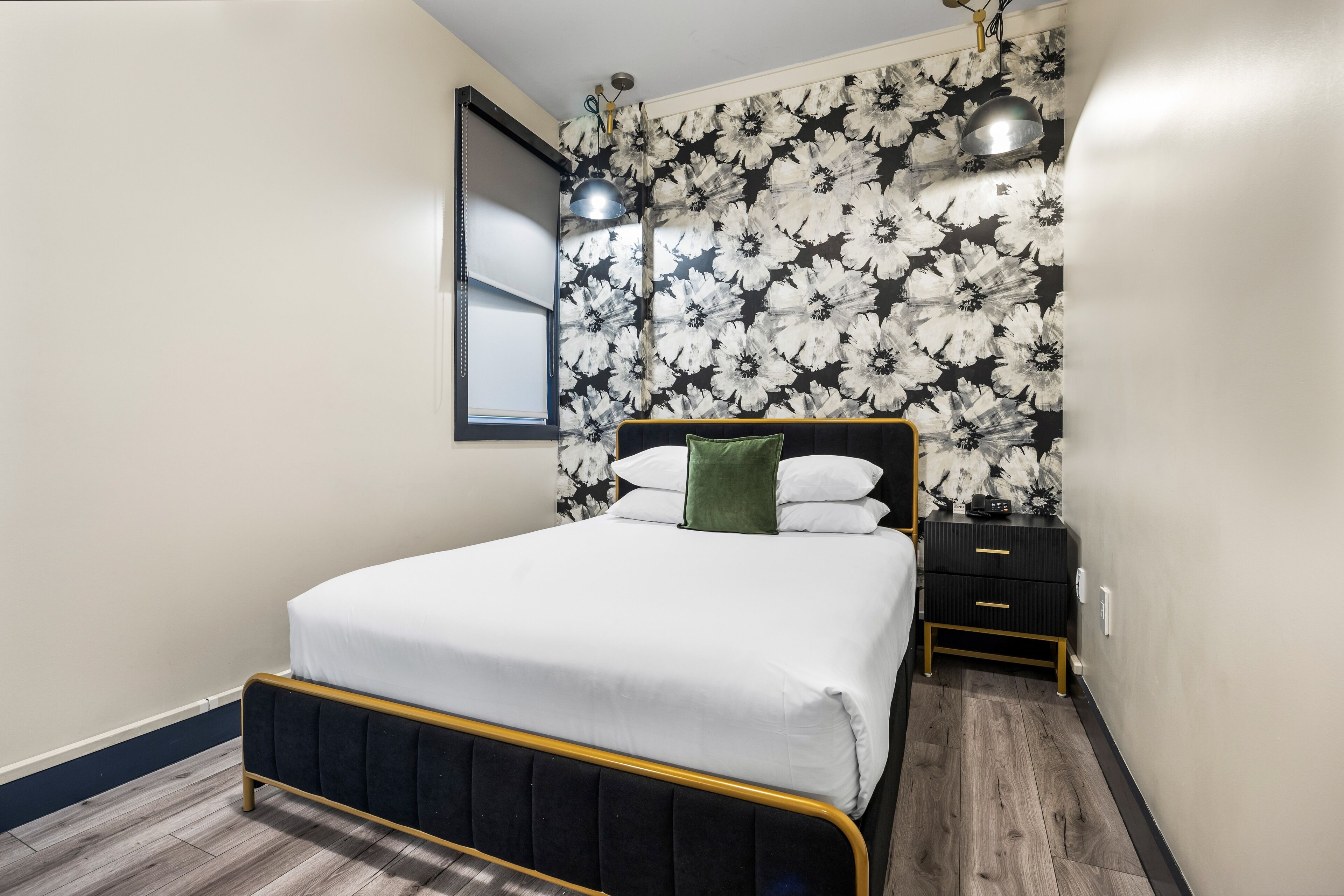 A bedroom with a bed, a nightstand, and a wall-mounted lamp.