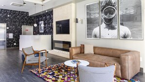 A modern living room with a brown leather sofa, two patterned armchairs, a coffee table, and a fireplace. - Hotel EPIK (San Francisco)