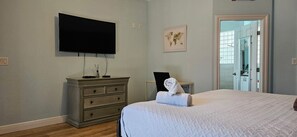 A bedroom with a bed, a dresser, a television, and a door leading to another room. - Private Hot Tub, 3 Bdrm 3 Bath 1 Mi. To Beach (Lake Worth)