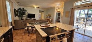 A kitchen with a central island, dining area, and a living room with a sofa and TV. - Private Hot Tub, 3 Bdrm 3 Bath 1 Mi. To Beach (Lake Worth)