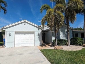 Une maison de plain-pied avec un garage, une véranda et une pelouse bien entretenue.
