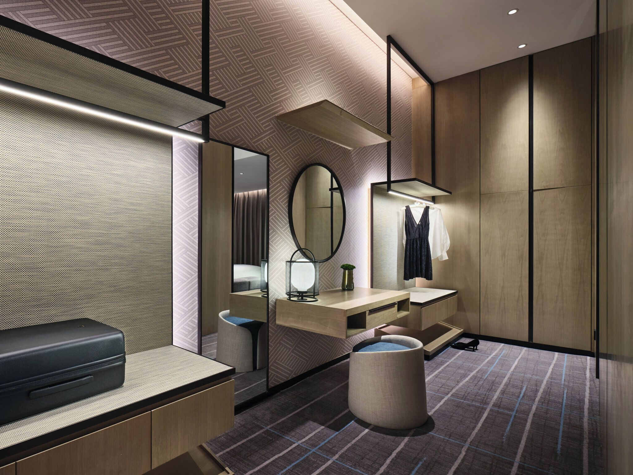 A modern bathroom with a mirror, vanity, and a black suitcase on the left.