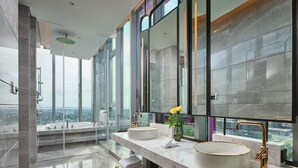 Een moderne badkamer met twee grote wastafels, een grote spiegel en uitzicht op de stad.