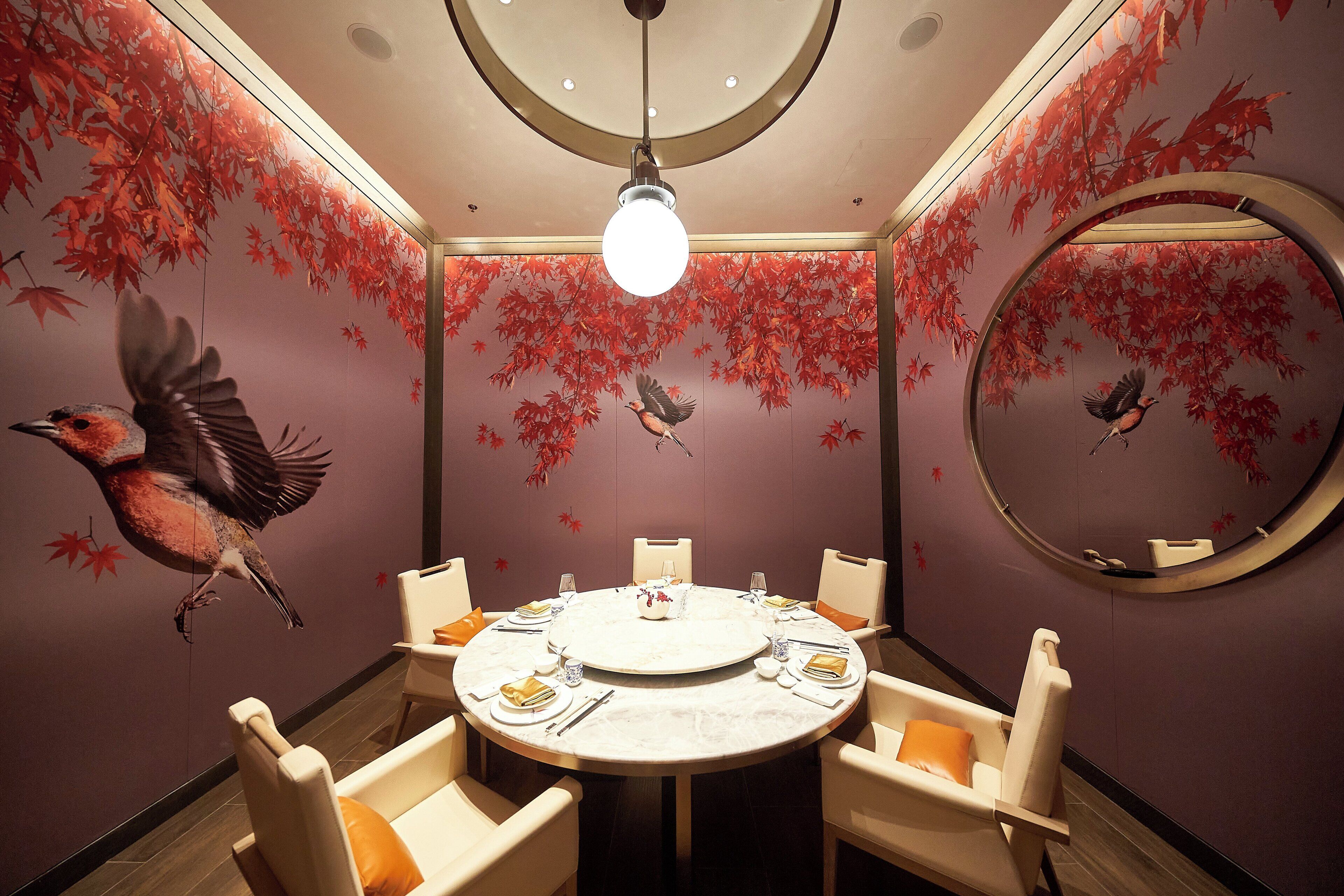 A dining area with a round table, chairs, and a central light fixture.