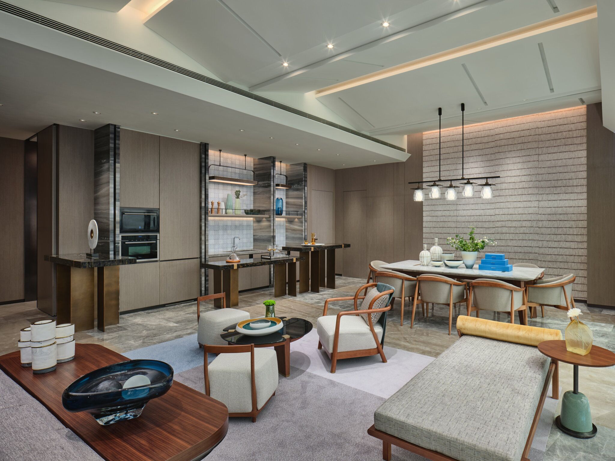 A modern kitchen with a central island, a dining area with a round table and chairs, and a seating area with sofas and a coffee table.