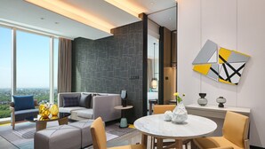 Een moderne hotelkamer met een groot raam, een bank, een eettafel en een decoratieve vaas.
