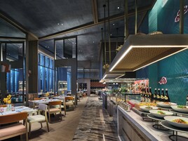 Un interior de restaurante moderno con techos altos, ventanas amplias y diversas opciones de asientos.