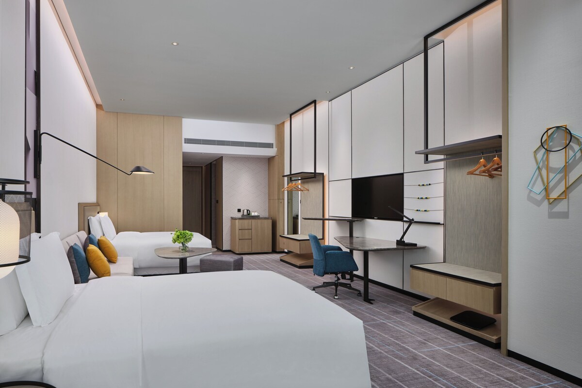 Een moderne hotelkamer met een groot bed, een bureau, een stoel, een televisie en een kledingkast.