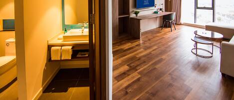 Une chambre d’hôtel moderne avec un plancher en bois, une grande fenêtre, un téléviseur à écran plat, un bureau et une chaise.