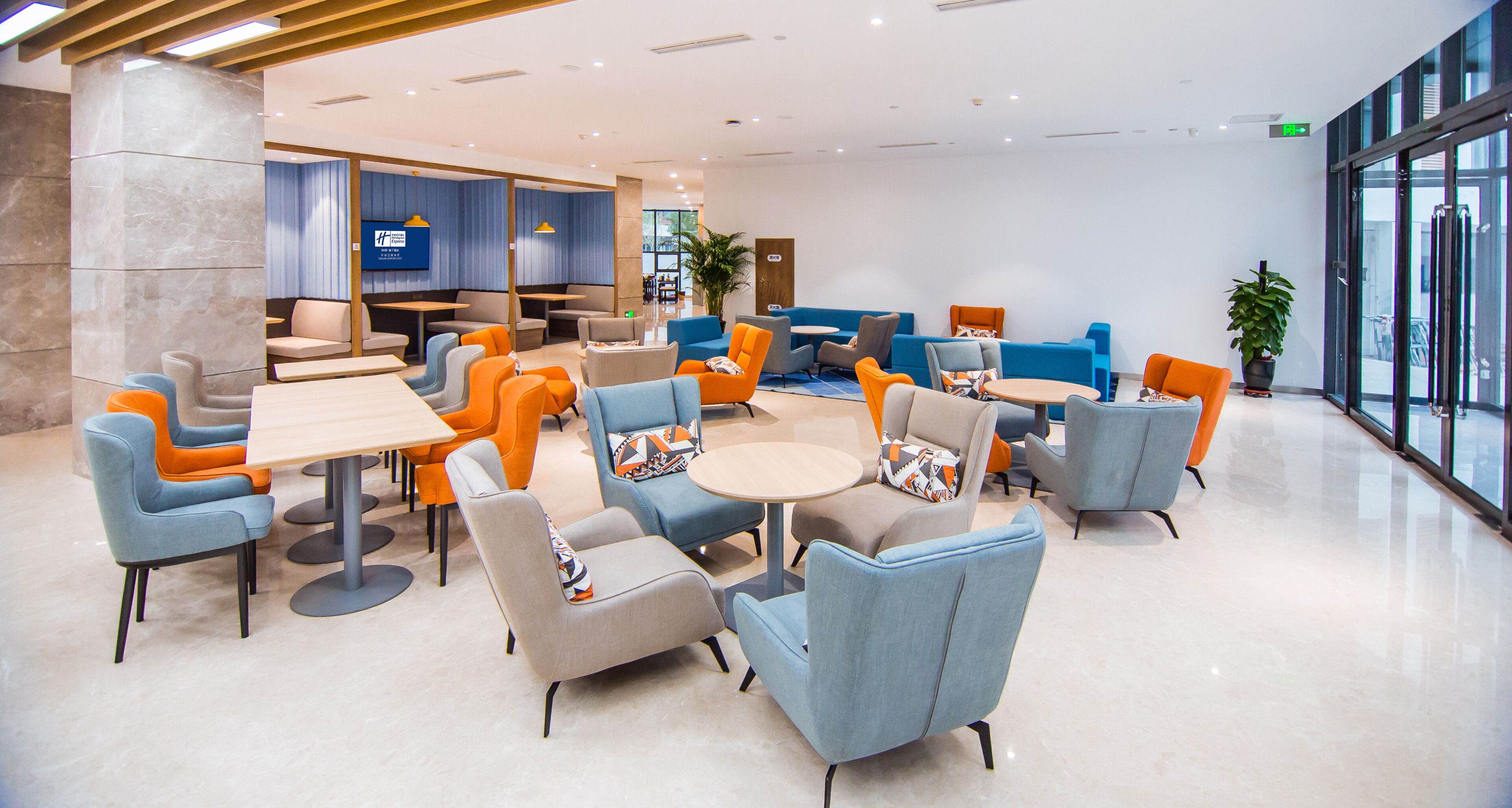 A modern hotel lobby with a variety of seating options, including sofas and chairs, arranged around a central coffee table.