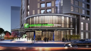 Un hôtel moderne à la façade incurvée, doté de grandes fenêtres et d’une entrée imposante agrémentée d’une fontaine.