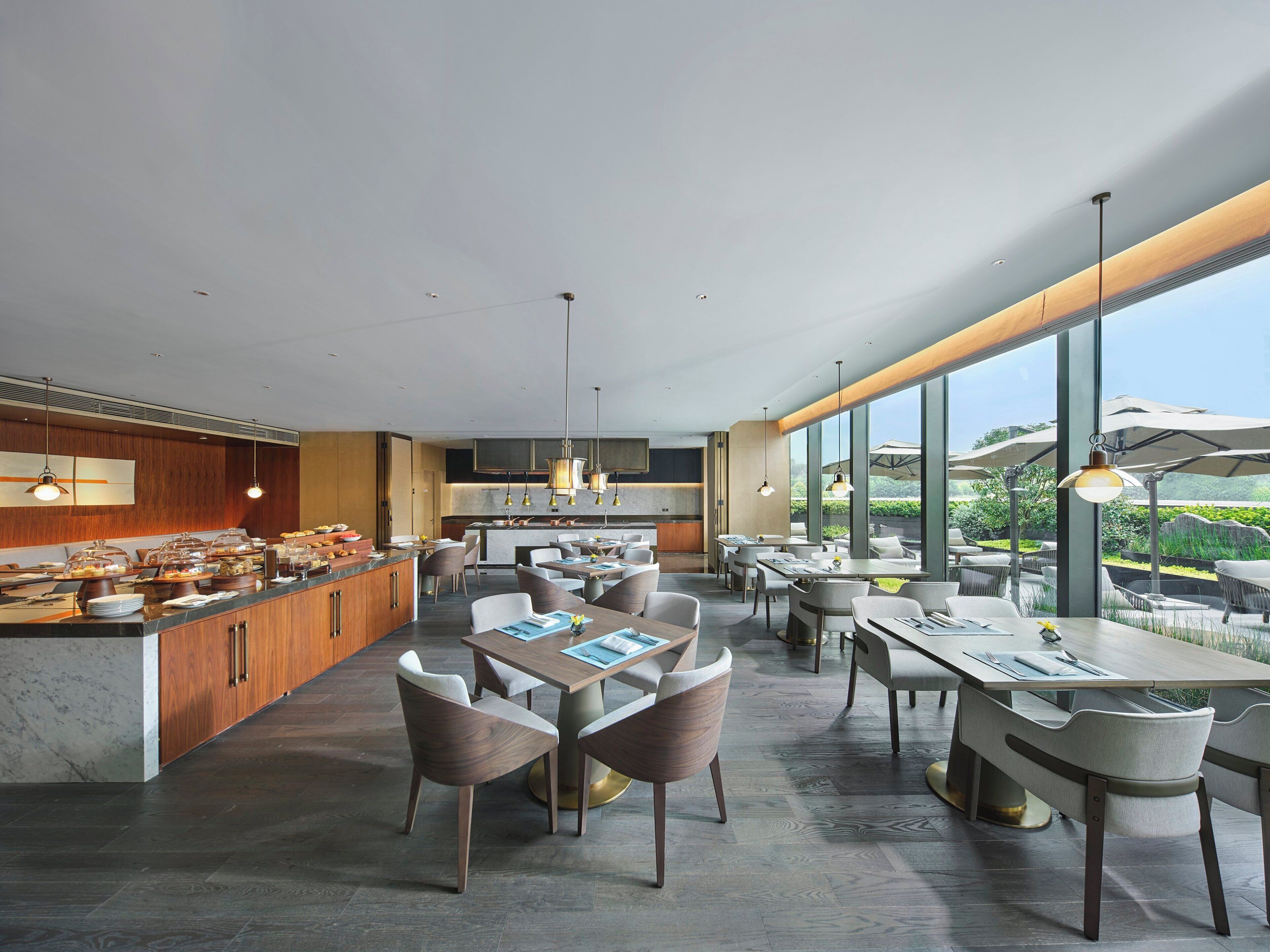 A modern dining area with a central island, seating arrangements, and large windows offering views.