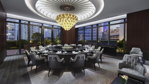 A modern dining room with a round table, chairs, and a chandelier. Large windows offer views of the cityscape. - Intercontinental Dongguan by IHG (Dongguan)