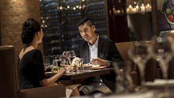 A couple dining at a restaurant with a brick wall and city view in the background.