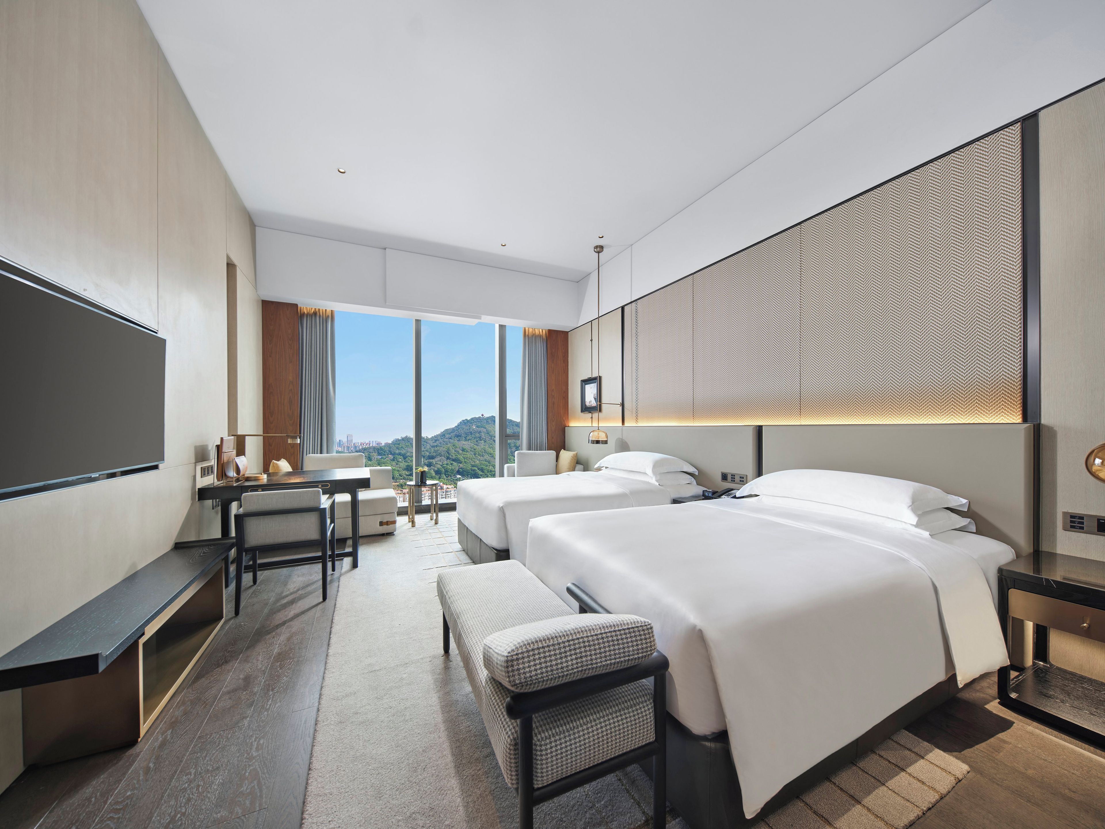 A modern hotel room with a large bed, a desk, and a seating area.