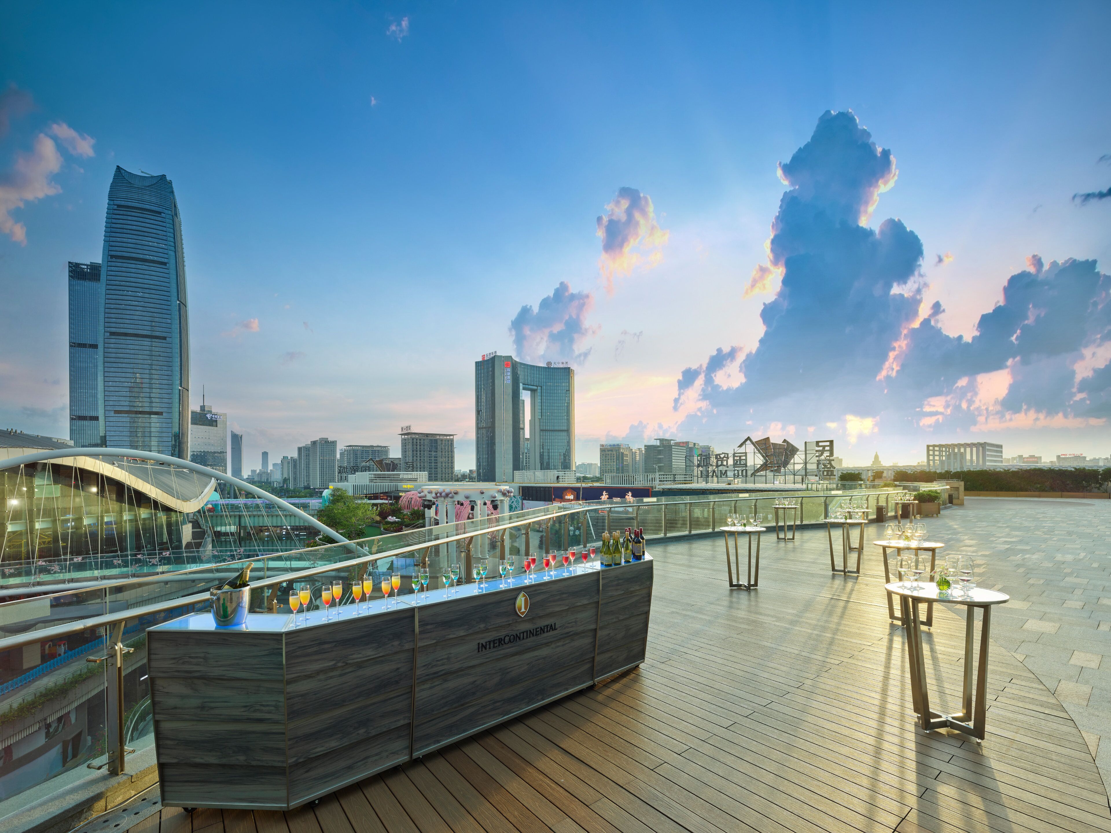 A rooftop bar with a view of the city skyline, featuring modern buildings and a clear sky.