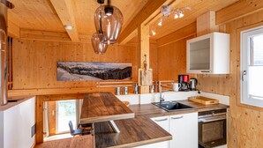 Una cocina moderna con paredes de madera, una isla grande, electrodomésticos de acero inoxidable y un cuadro de un paisaje montañoso.