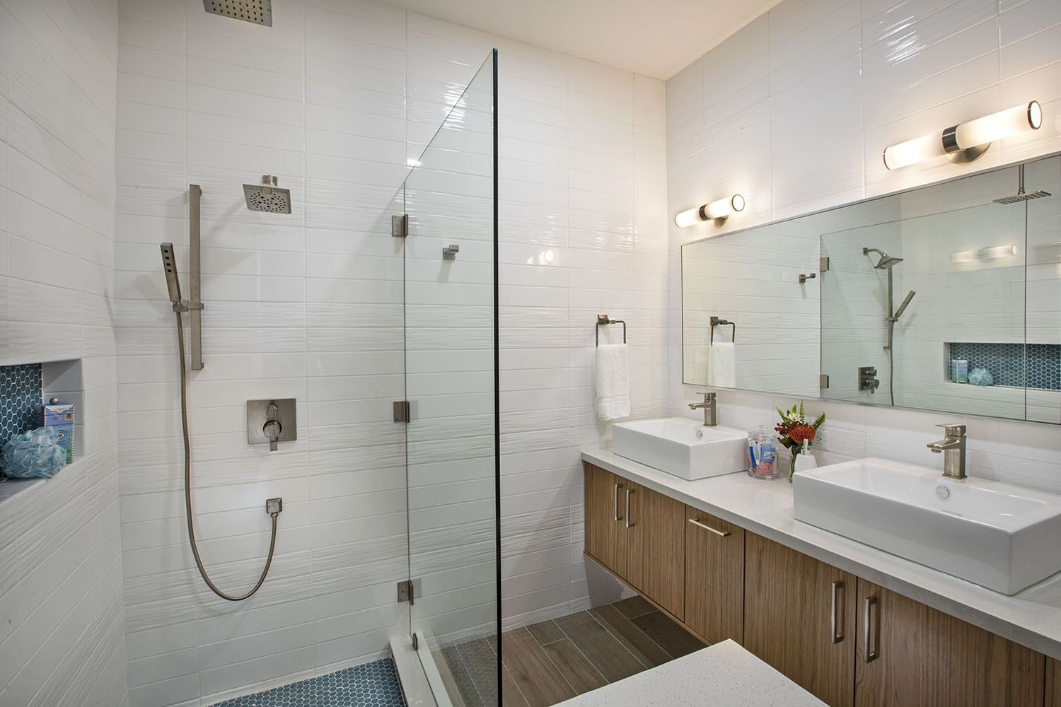 A modern bathroom with a glass-enclosed shower, two sinks, and a large mirror.