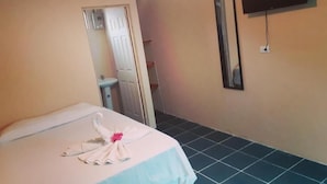 A hotel room with a bed, a TV mounted on the wall, and a bathroom visible through an open door. - Guesthouse Morpho CR (Quepos)