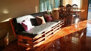 Una habitación con un sofá de madera, una mesa de comedor con sillas y baldosas de suelo con diseño.