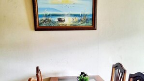 Un comedor con una mesa de madera, bancos acolchados y un cuadro en la pared.