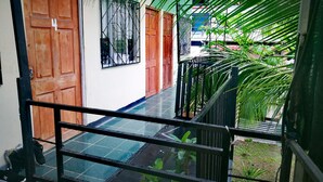 Un espacio exterior techado con suelo de baldosas, puertas de madera y barandillas de metal.