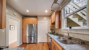 A modern kitchen with wooden cabinets, stainless steel appliances, granite countertops, and a window with a view of the outside.