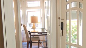 A hallway with a wooden floor leading to a dining area with a table and chairs.