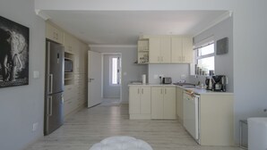 Eine moderne Küche mit Kühlschrank, Mikrowelle und Kaffeemaschine. Eine Tür führt in einen weiteren Raum.