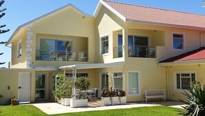 Ein zweistöckiges Haus mit Balkon, überdachter Terrasse und gepflegtem Rasen.