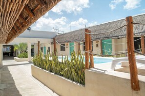 A poolside area with a thatched roof, a pool, and a lounge chair. - Hotel Pelicano (Chiquilá)