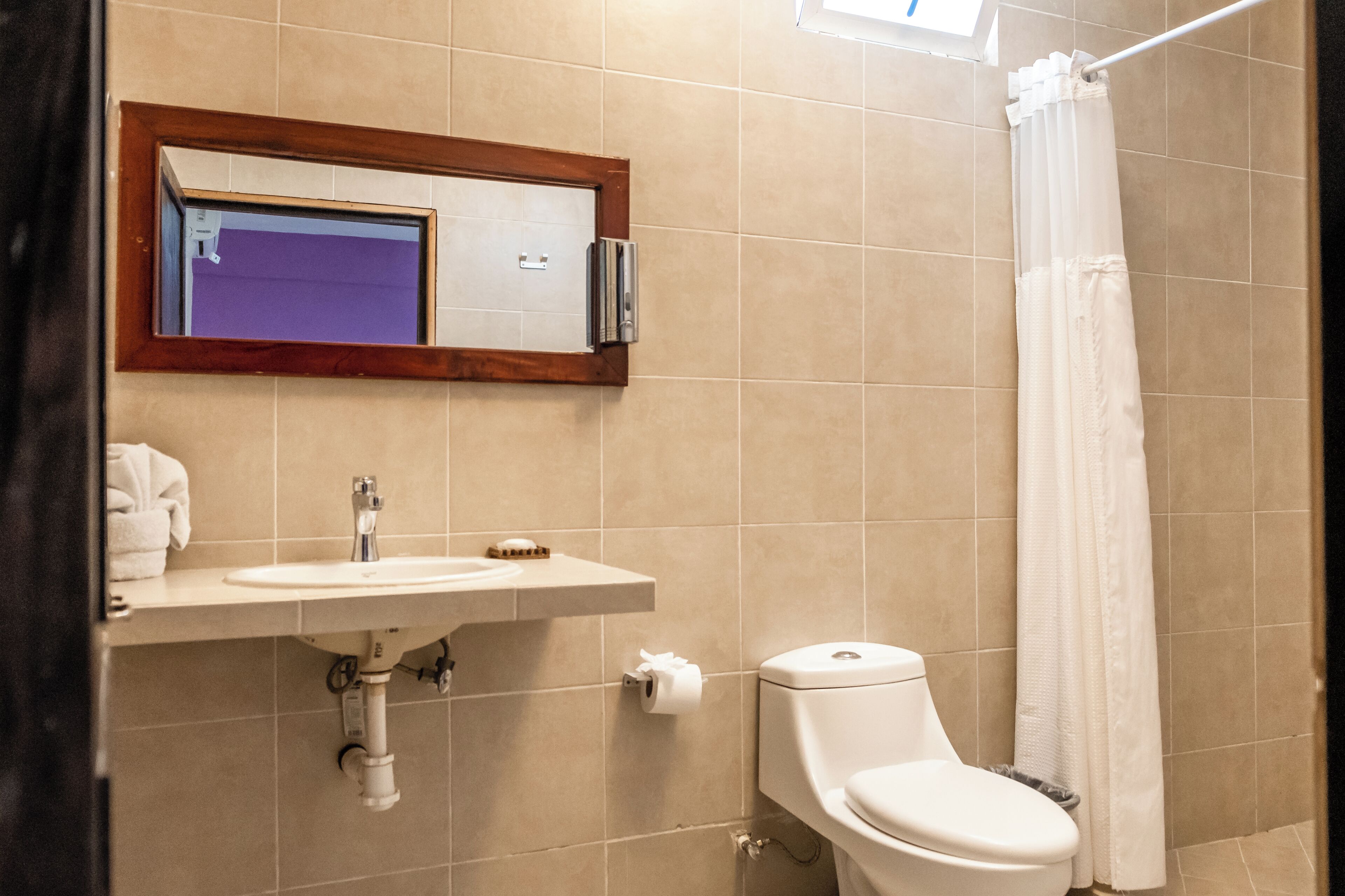 A bathroom with a sink, toilet, and a mirror above the sink.