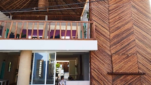 A building with a thatched roof structure, a balcony with wooden railings, and a modern facade with a geometric pattern. - Hotel Pelicano (Chiquilá)