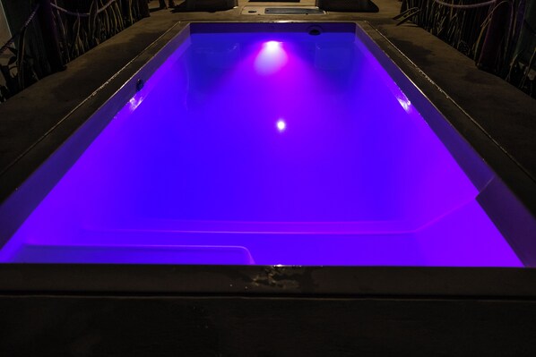 A rectangular pool with a blue illuminated surface, surrounded by a dark frame.