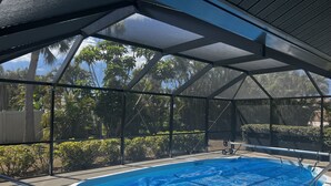 Piscina interna com vista para palmeiras e área coberta.