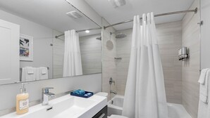 Un bagno moderno con lavandino, specchio e water bianchi.