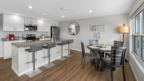 Una cocina moderna con armarios blancos, electrodomésticos de acero inoxidable y una barra con taburetes.